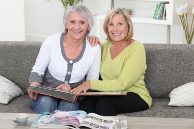 Mother and daughter looking at a picture album together clipart
