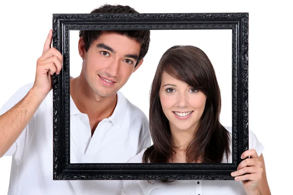 Couple holding empty picture frame — Stock Photo, Image