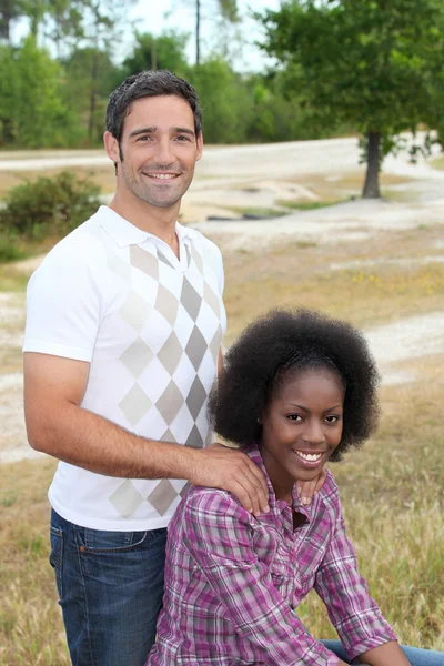 Interracial par avkopplande i parken — Stockfoto