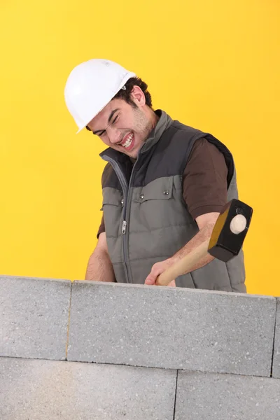 Trabalhador batendo uma parede com uma marreta — Fotografia de Stock