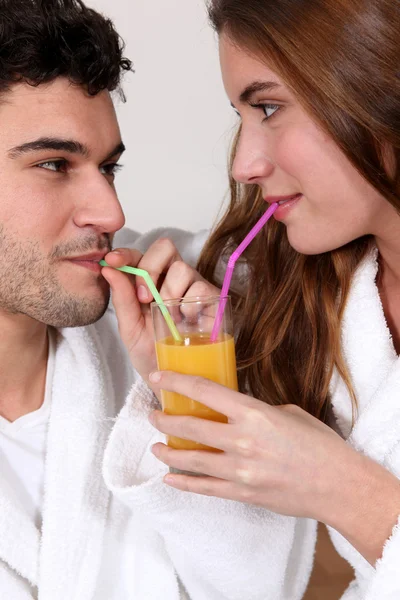 Casal compartilhando um copo de suco de laranja — Fotografia de Stock