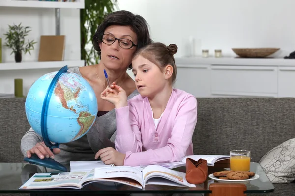 Женщина помогает внучке закончить домашнее задание по географии — стоковое фото