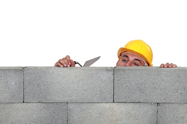 Каменщик, смотрящий через низкую стену — стоковое фото