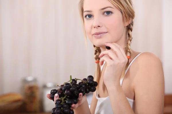 Kvinna äta röda druvor Stockbild