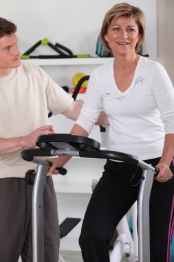 Woman with personal trainer in gym clipart