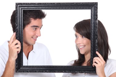 Young couple behind photo frame clipart