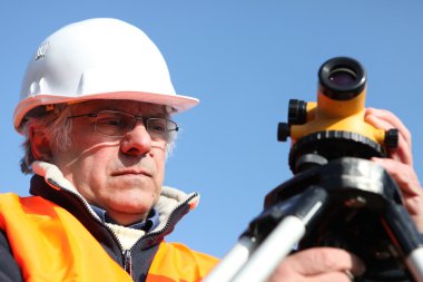 Mature surveyor in construction site clipart