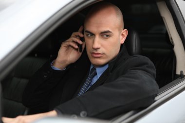 Businessman using a phone in his car clipart