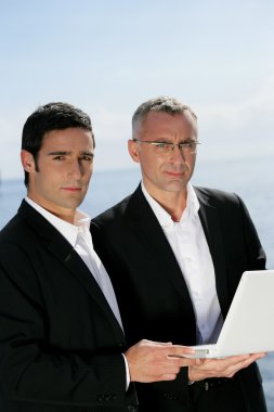 Two businessmen outdoors with laptop clipart