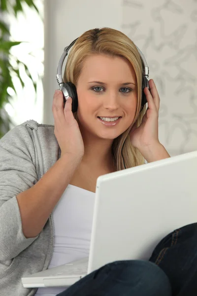 Молода дівчина слухає свій ноутбук на навушниках — стокове фото