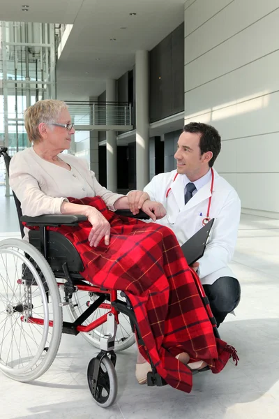 Läkare pratar med en äldre kvinna i rullstol — Stock fotografie