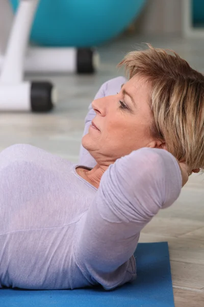 Γυναίκα που κάνει sit-ups σε γυμναστήριο χαλί — Φωτογραφία Αρχείου