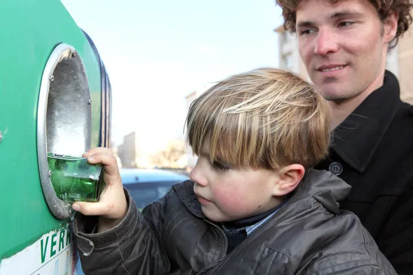 Petit garçon mettant une bouteille en verre dans une poubelle de recyclage — Photo