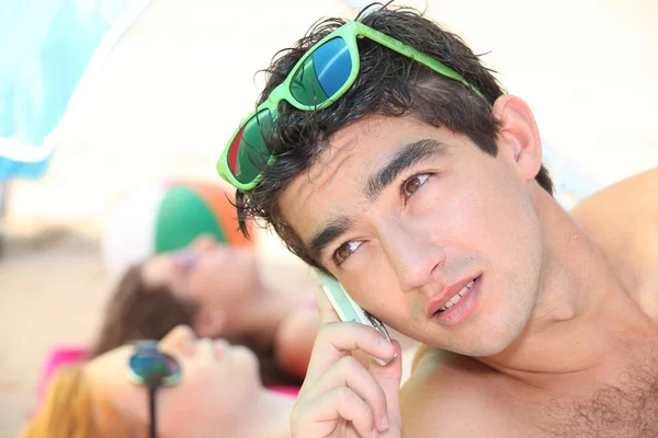 Мужчина-подросток на пляже делает телефонный звонок — стоковое фото