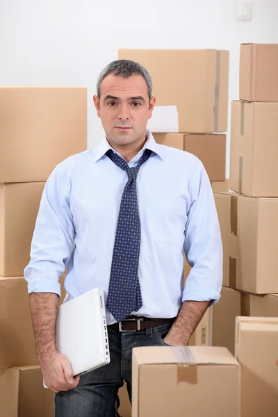 Homem no depósito de armazenamento cercado por caixas — Fotografia de Stock