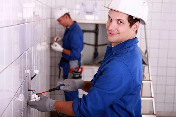 Eletricistas fiação de uma grande sala de azulejos brancos — Fotografia de Stock
