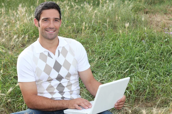 Άνθρωπος εξετάζοντας το laptop του σε ένα πεδίο — Φωτογραφία Αρχείου