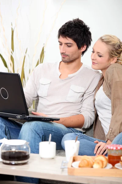 Paar kijken naar een laptop tijdens het ontbijt — Stockfoto