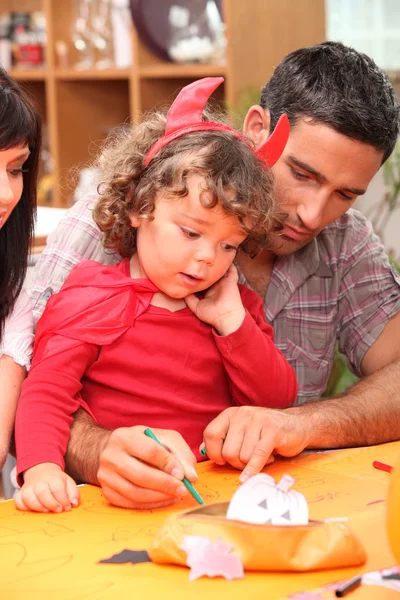 Parents helping child with Halloween decorations — Stock Photo, Image