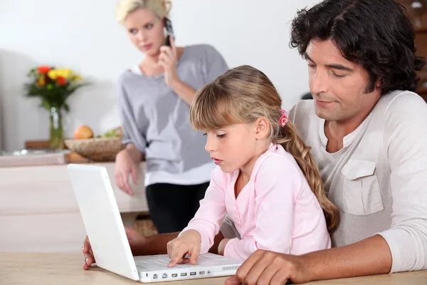 Отец и дочь за компьютером, мать за телефоном — стоковое фото