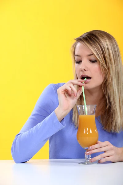 Женщина пьет апельсиновый сок с соломинкой — стоковое фото