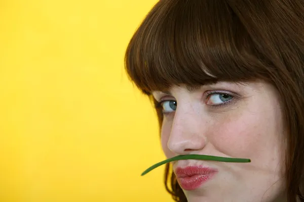 Mulher segurando um feijão verde entre os lábios e o nariz — Fotografia de Stock