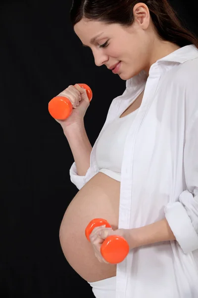 Беременная женщина поднимает гантели — стоковое фото