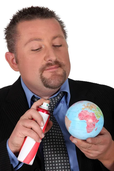 Empresario rociando el mundo con un aerosol — Foto de Stock