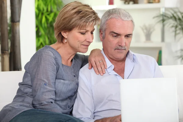 Casal de meia-idade olhando para seu laptop — Fotografia de Stock