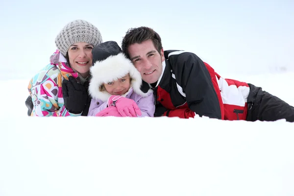 Pais e filha deitada na neve — Fotografia de Stock