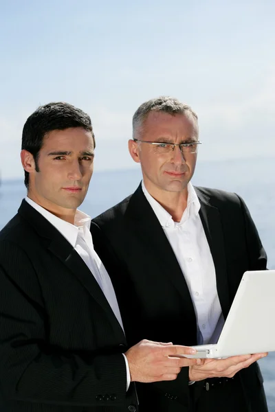 Two businessmen outdoors with laptop — Stock Photo, Image