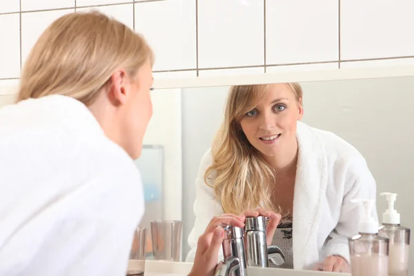 Kvinna i ett badrum, tvätta händerna framför en spegel — Stockfoto