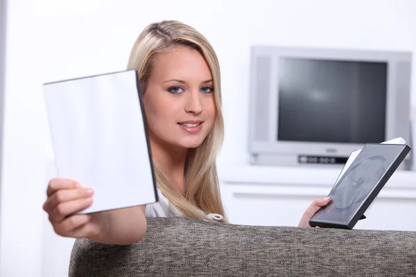Mujer joven eligiendo un DVD con una cubierta en blanco para su imagen —  Fotos de Stock