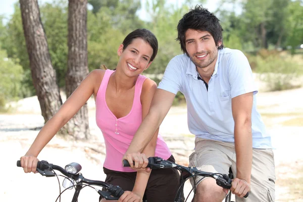 Couple cycling through a coastal pine forest — Stock Photo, Image