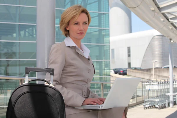 Kobieta na laptopa poza Lotnisko — Zdjęcie stockowe