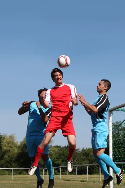 3 junge Männer spielen Fußball — Stockfoto