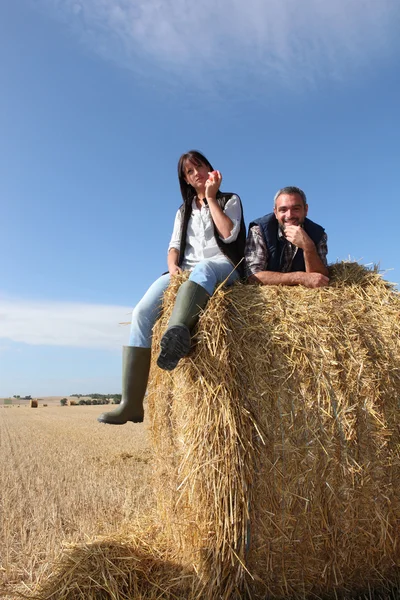 Couple sitting on bail of hay — Stock Photo, Image