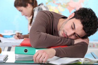 Young man sleeping during a university lecture clipart