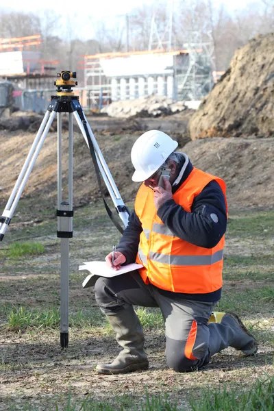 A land surveyor writing in his notebook while talking on the phone — Stock Photo, Image