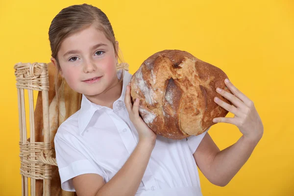 Proud young girl holding up a bread loaf — Stock Photo, Image