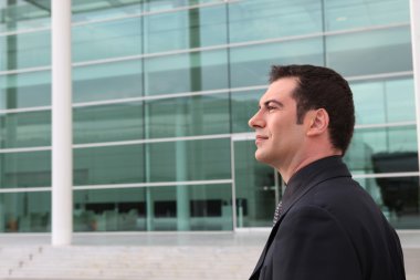 Businessman outside a glass fronted building clipart