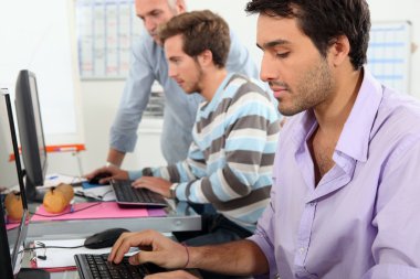 Young men working on computers clipart