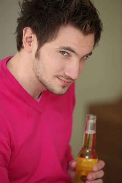 Uomo dai capelli scuri con in mano una bottiglia di birra — Foto Stock