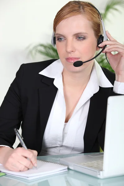 Vrouw met behulp van een hoofdtelefoon op haar laptop — Stockfoto