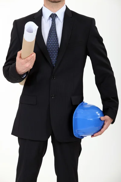 Arquiteto carregando seu capacete e uma planta — Fotografia de Stock