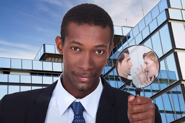 A black man showing a couple dispute through a magnifying glass — Stock Photo, Image