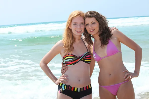 Dwie młode kobiety w bikini pozowanie w surf — Zdjęcie stockowe