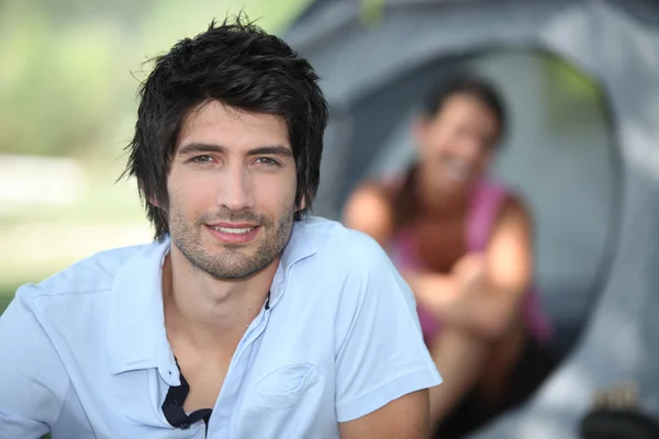 Young man camping with his girlfriend and tent out of focus in the backgrou — Stock Photo, Image