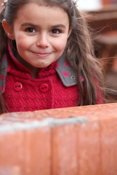 Bambina in piedi vicino al muro di mattoni — Foto Stock