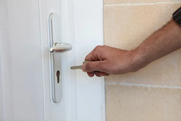 Um homem a pôr uma chave na porta da frente — Fotografia de Stock